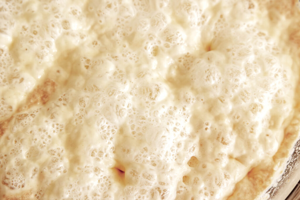 A close-up view of a dough starter bubbling with fermenting yeast.