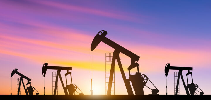 Silhouettes of oil pumpjacks operating in an oil field at sunset. Concept of crude oil extraction, energy production, and the petroleum industry.